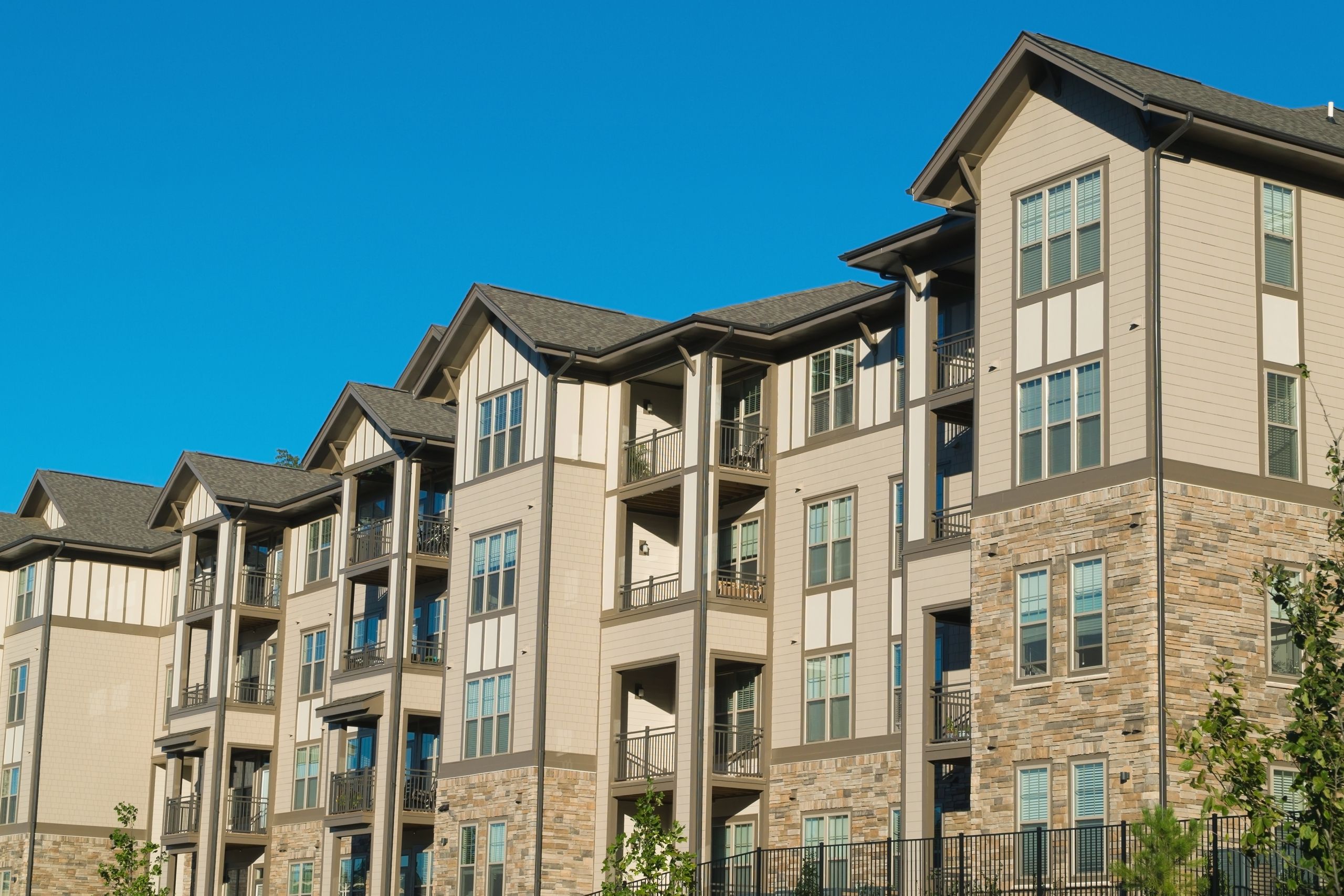 Townhouse Complex with tan colored commercial composite siding blue sky above